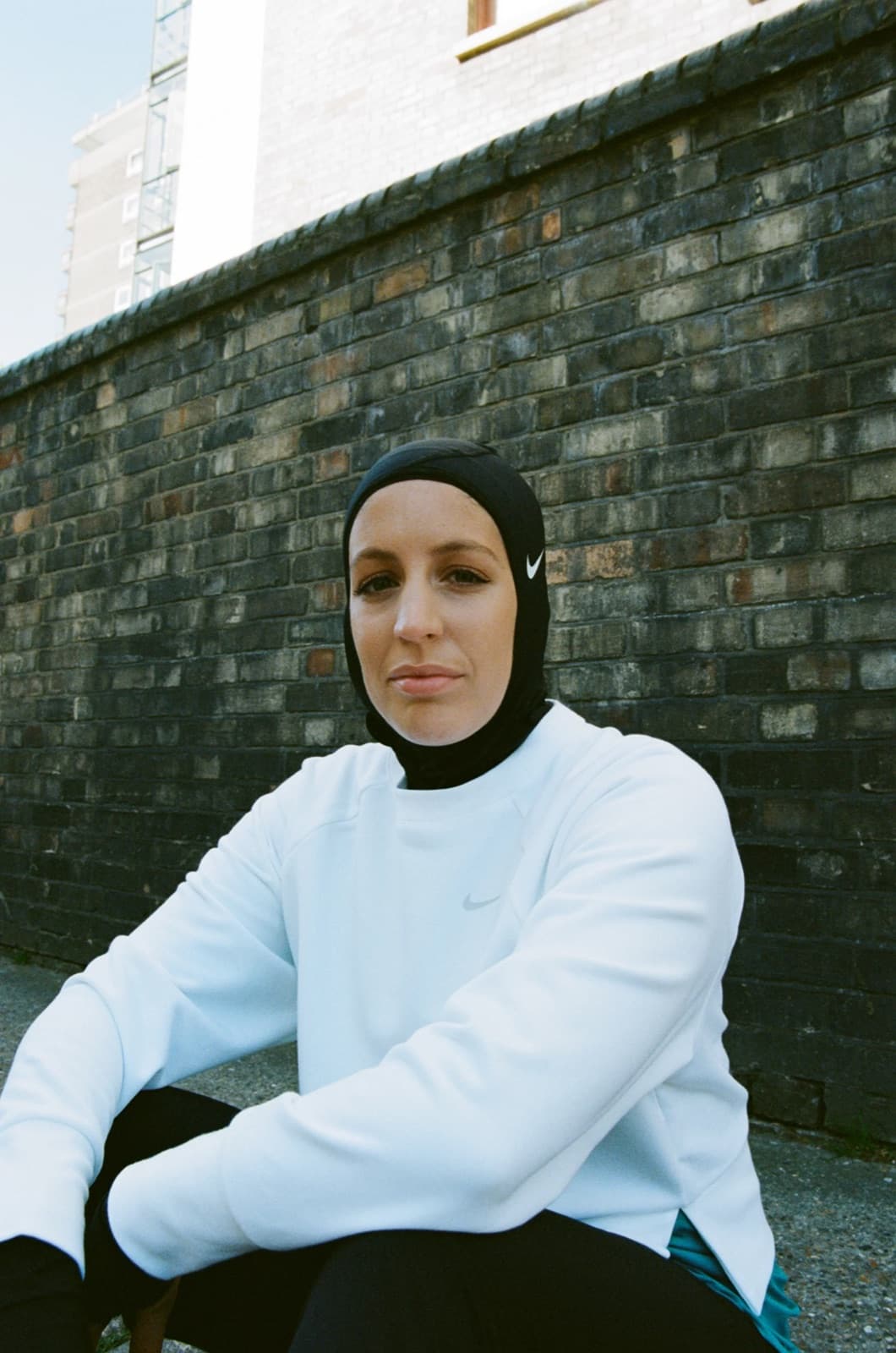 Nez Dally in a Nike Pro hijab, portrait against a brick wall
